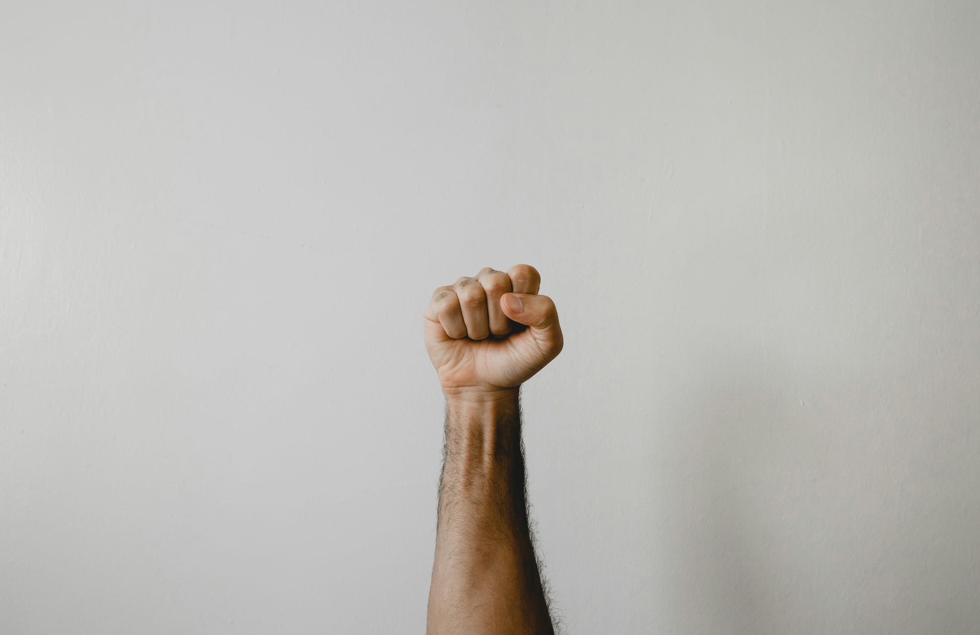 White hand raised and closed in form of a punch