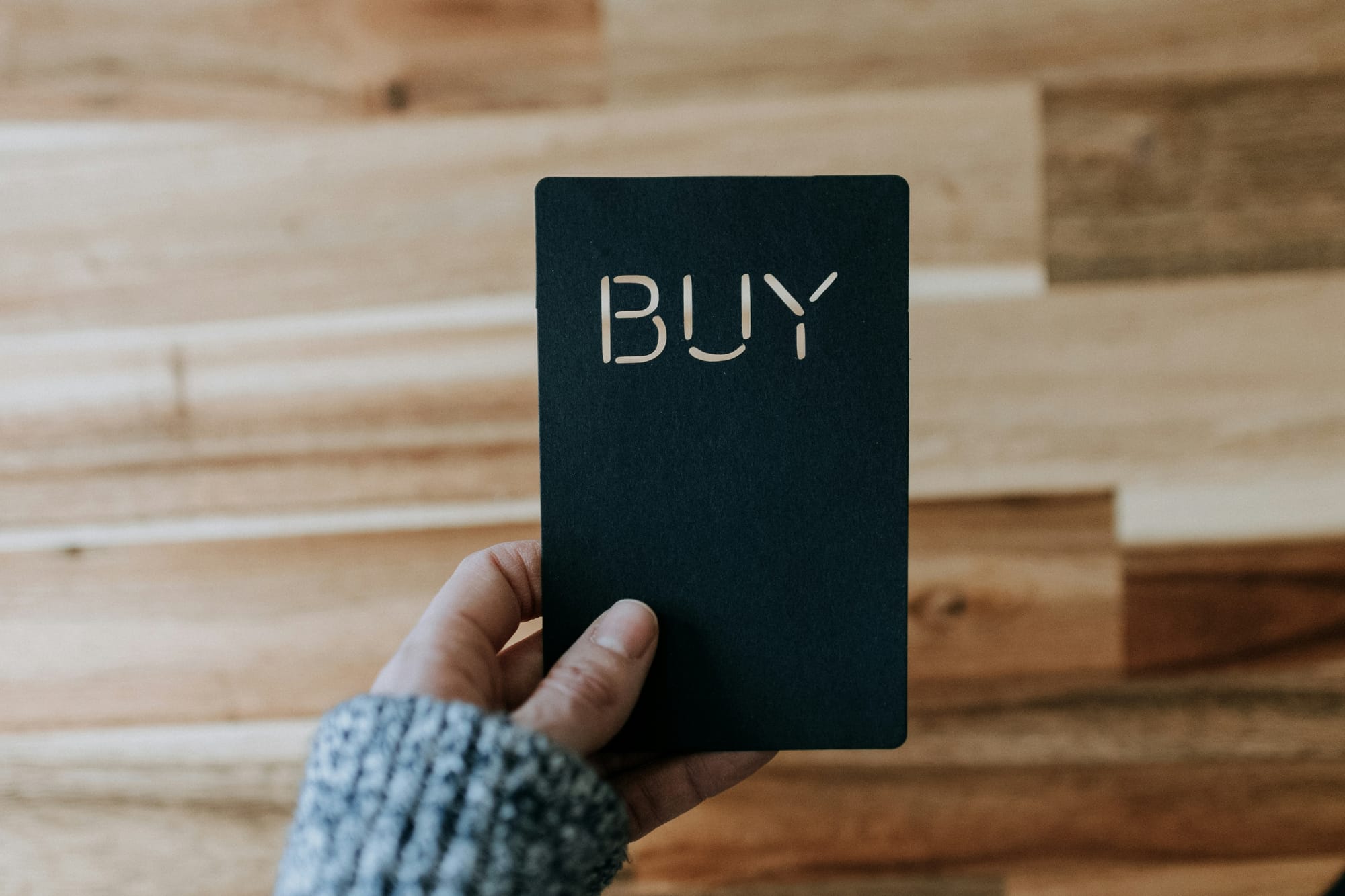Black buy sign being held up by a hand
